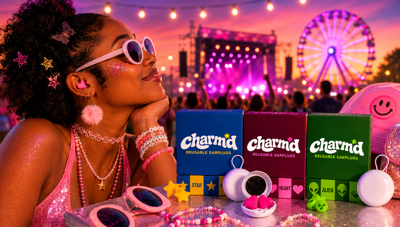 Festival-goer wearing pink heart-shaped earplugs at a colorful music festival with Charm'd reusable earplugs displayed in the foreground.