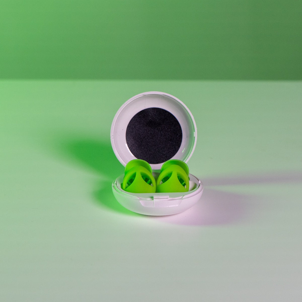 Two green alien charm earplugs resting together, fashion-forward hearing protection