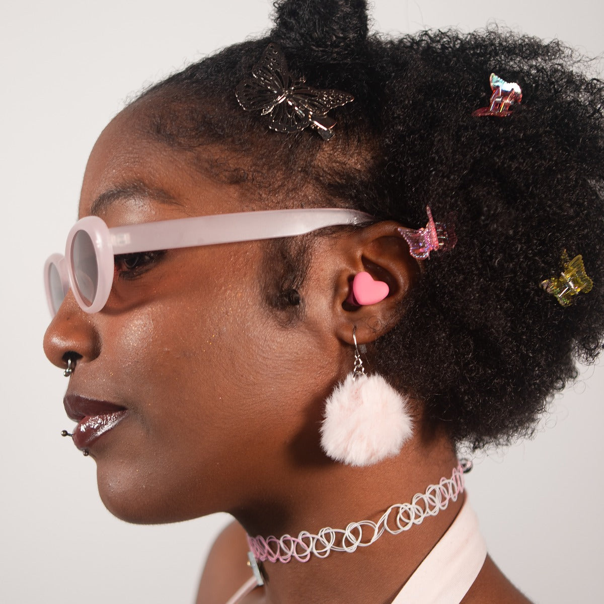 Pink heart-shaped Charm'd earplugs, a reusable pair shown against a soft studio backdrop