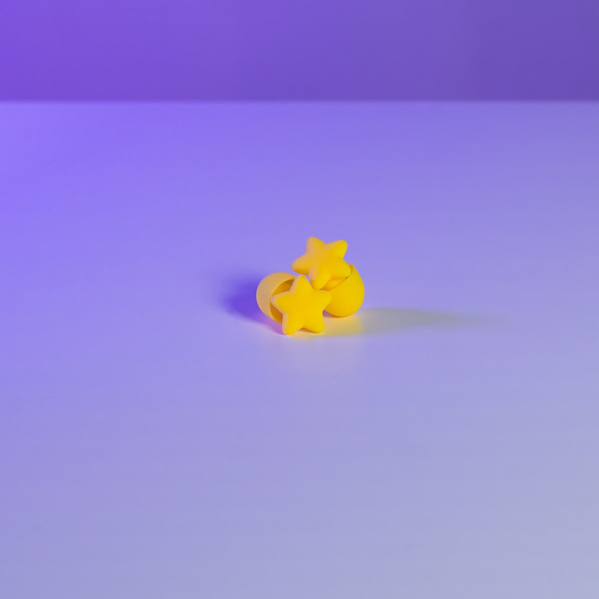 Pair of soft silicone star earplugs for concerts and festivals on a purple background